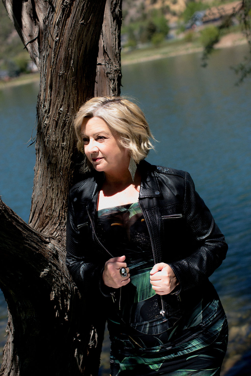 D. LeD in a leather jacket leaning against a tree by the lake